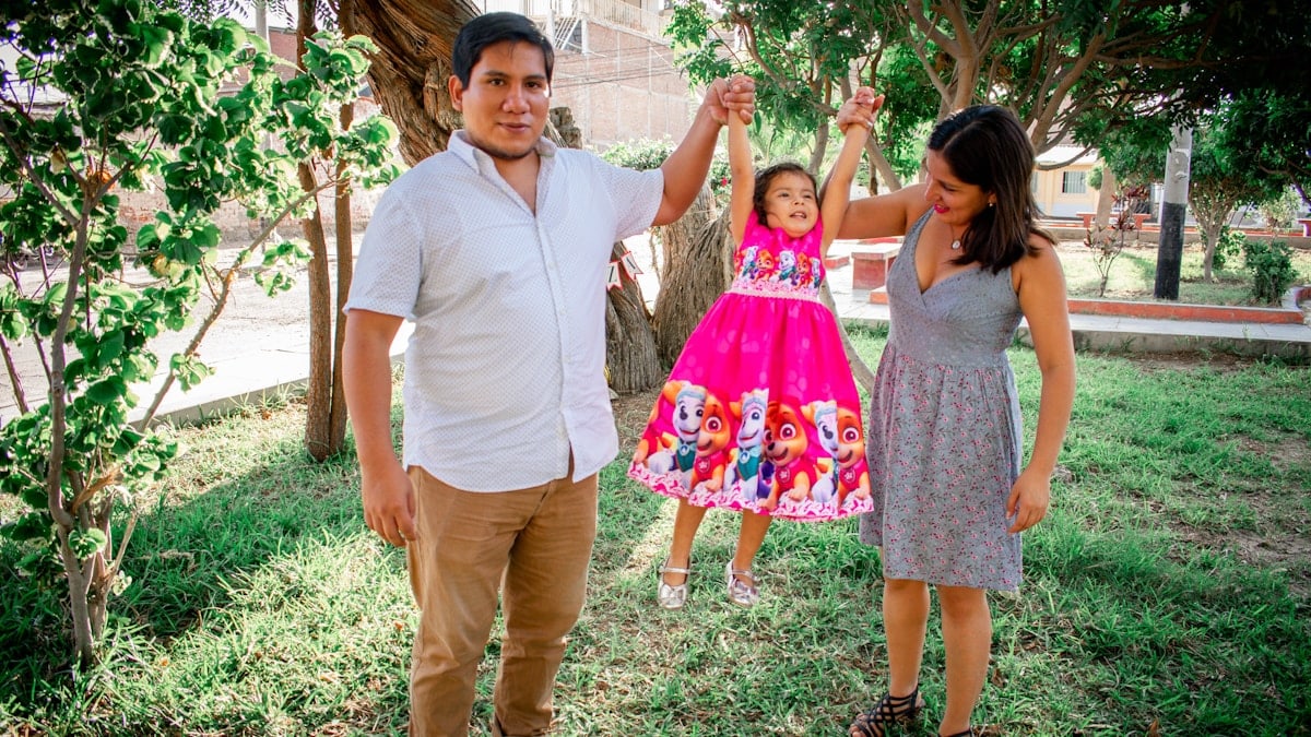 man in white polo shirt standing beside girl in pink floral dress